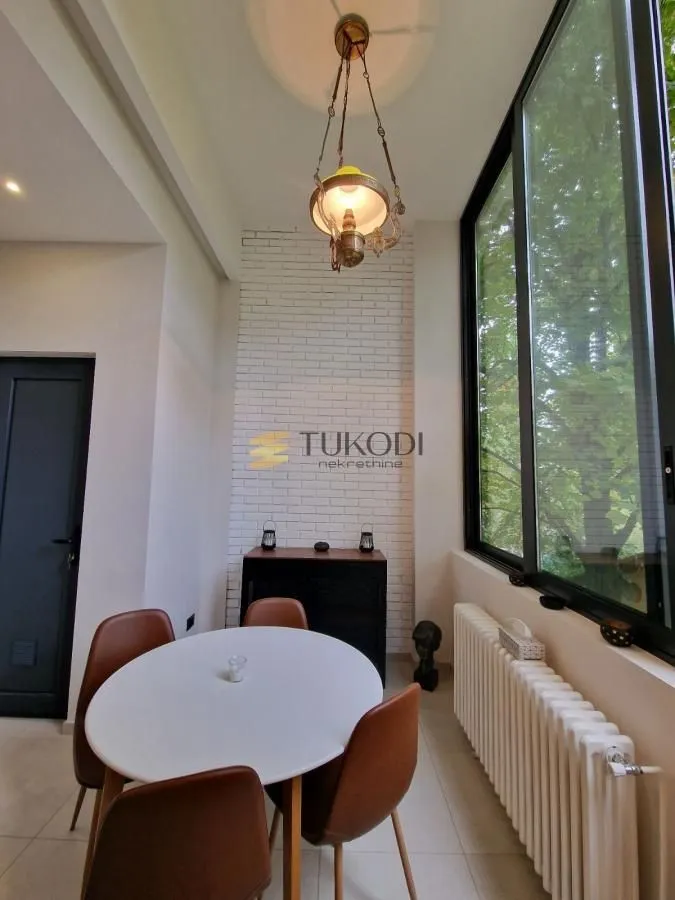 Dining area with a round table and large windows.