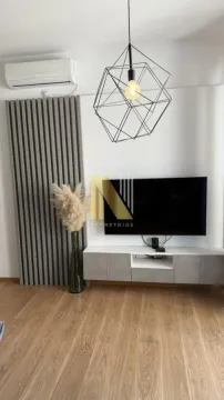 Dnevna soba sa TV-om, modernim lusterom i drvenim panelima na zidu. - image 3