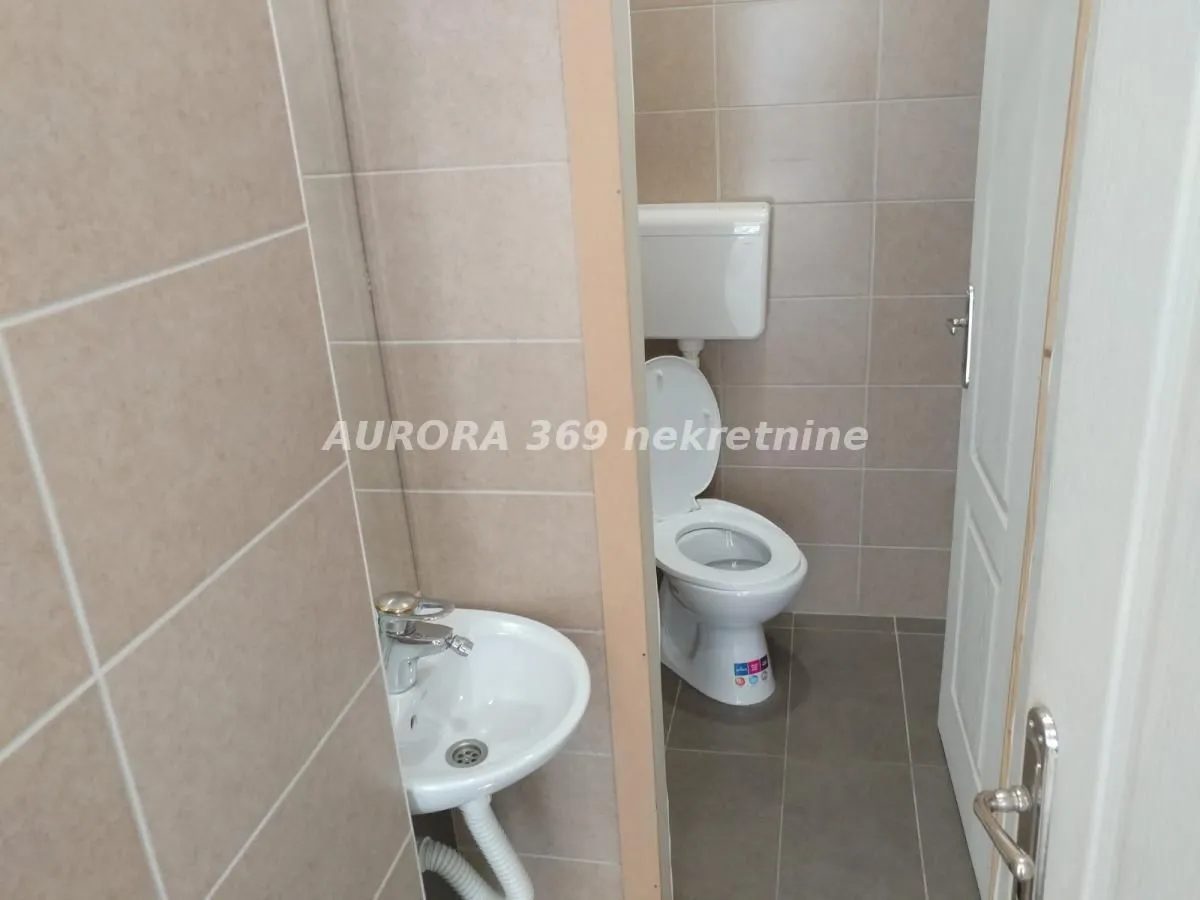 Small tiled bathroom equipped with a toilet and a sink.