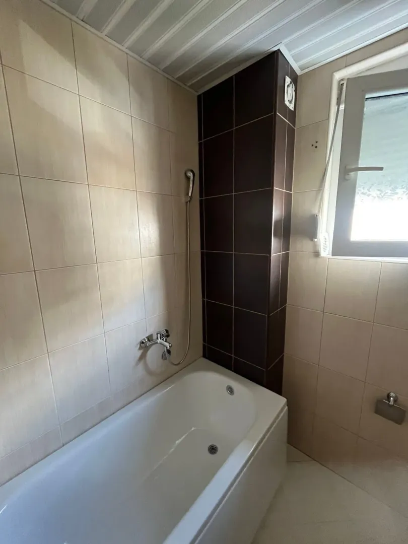 Smaller bathroom with a bathtub and ceramic tiles.