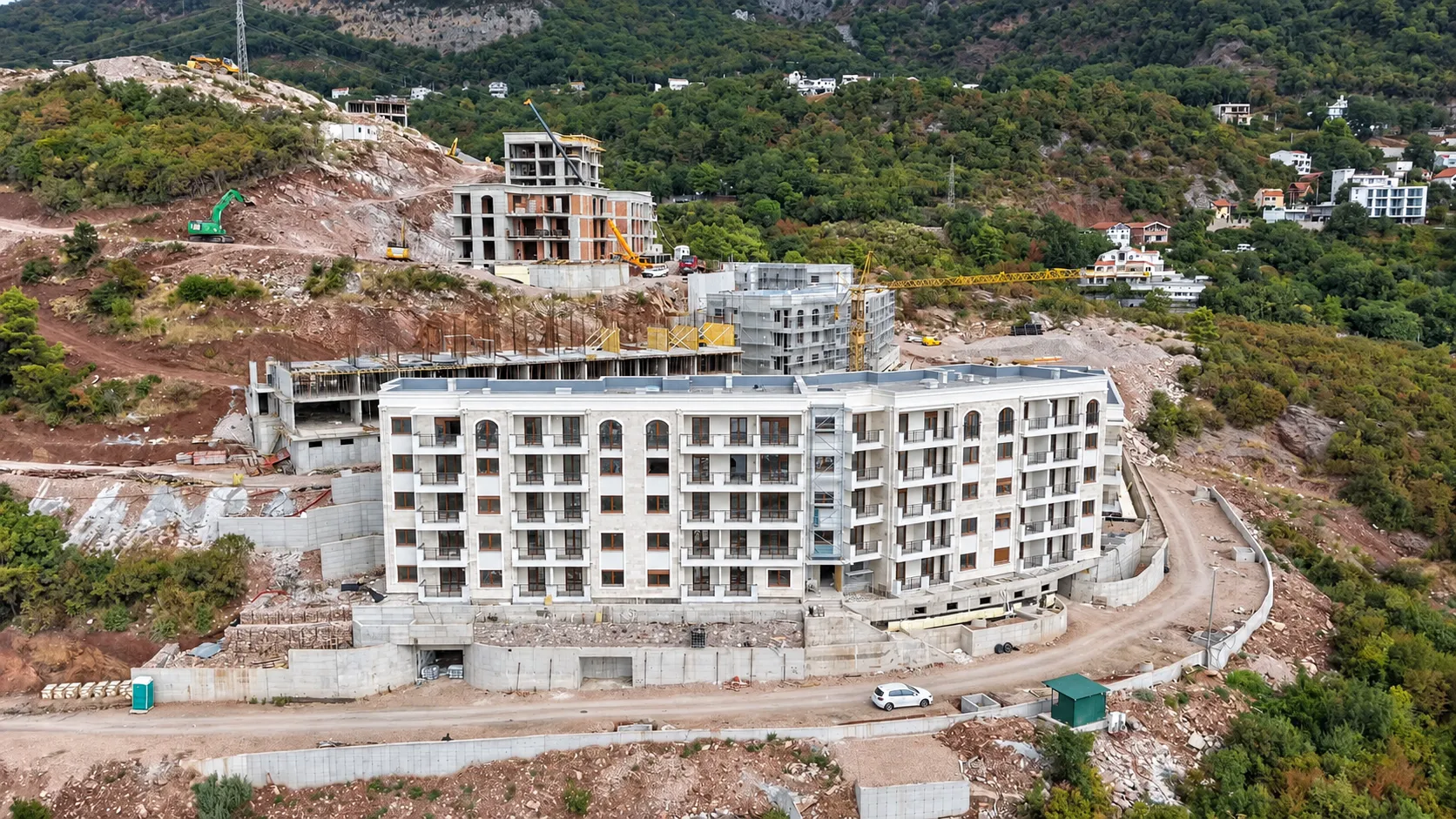 Pogled iz vazduha na stambeni objekat u izgradnji okružen zelenilom.