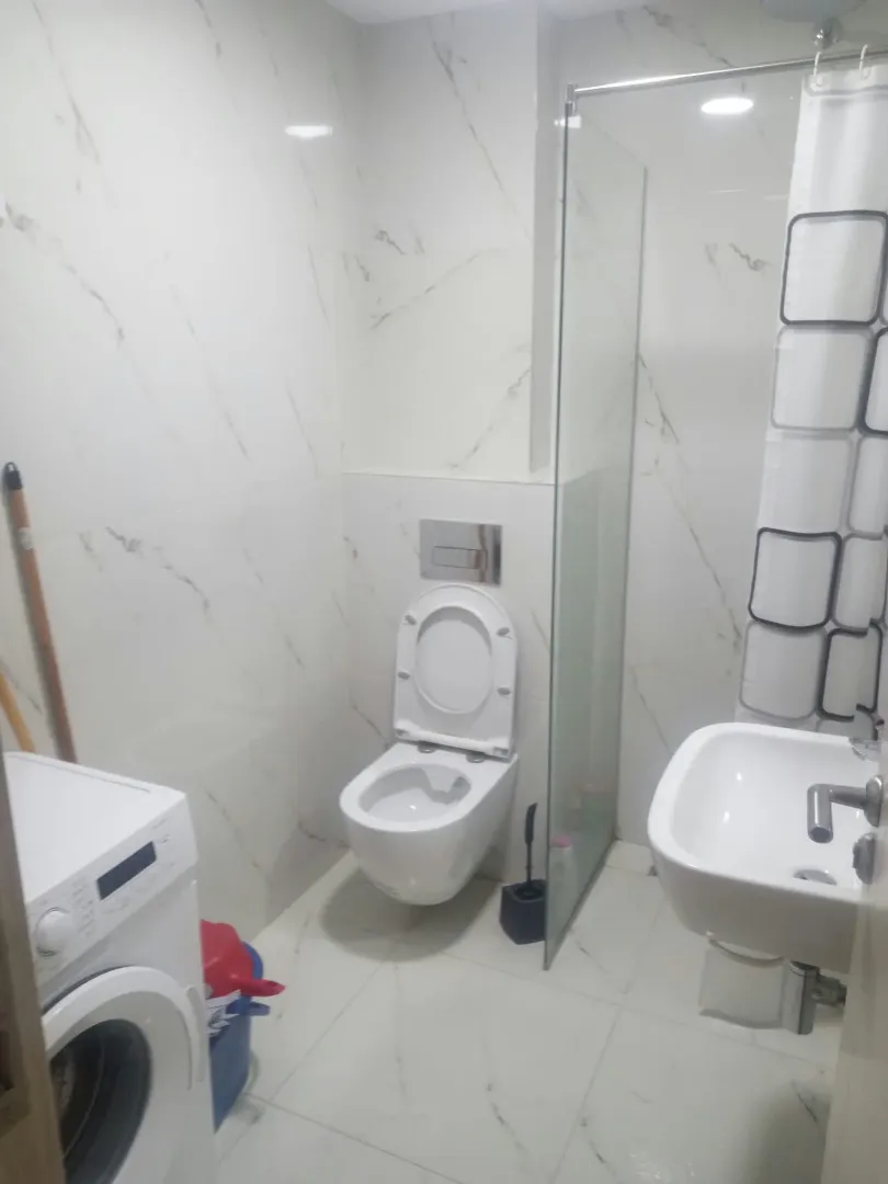 Modernly equipped bathroom with a walk-in shower, washbasin, and washing machine.