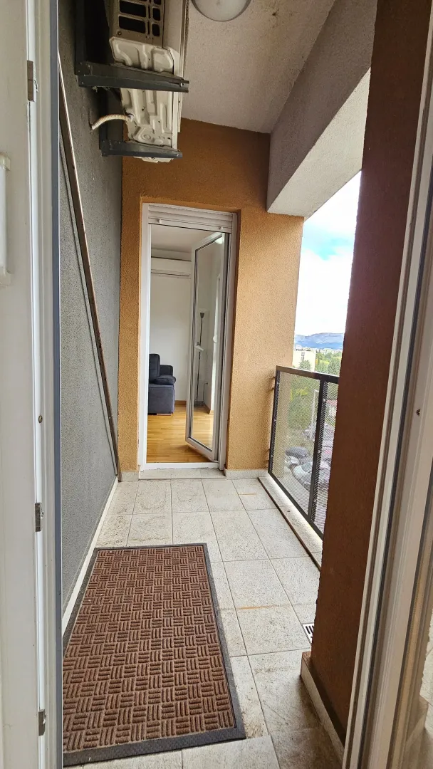 Small covered balcony with tiled flooring and a view of the surroundings.