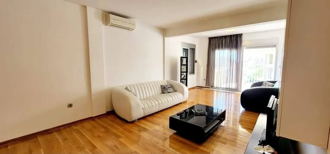 Spacious living room with sofa set and wooden floor.