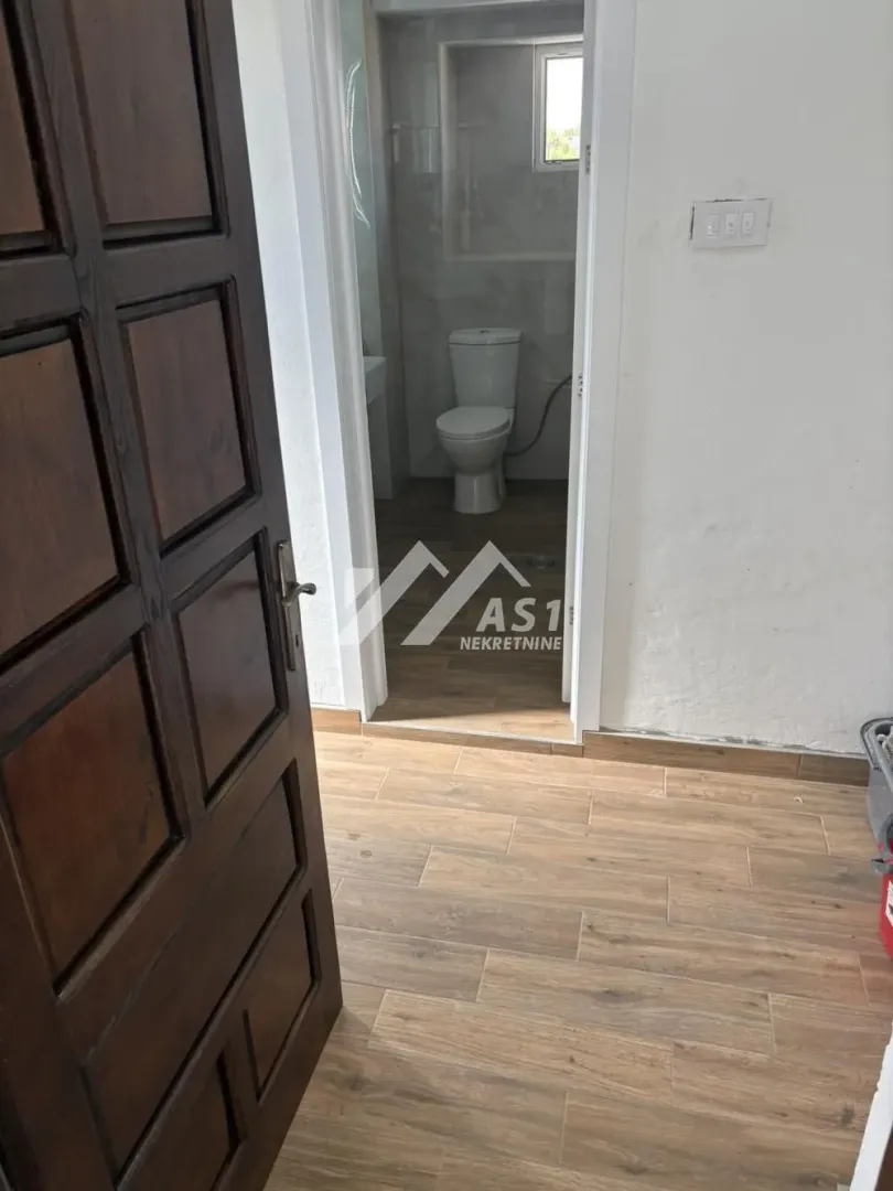 View from the hallway into the bathroom with wood-look ceramic tiles.