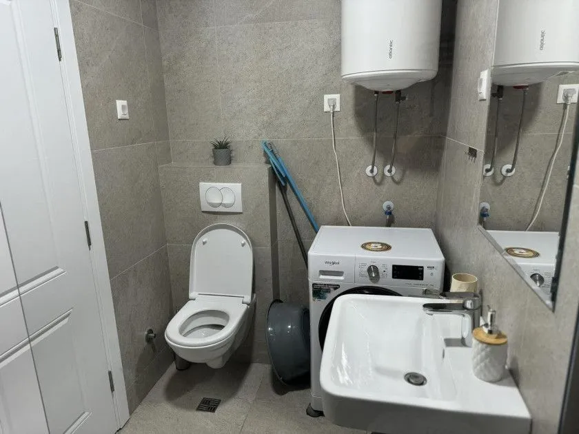 Bathroom with a toilet, sink, and washing machine.