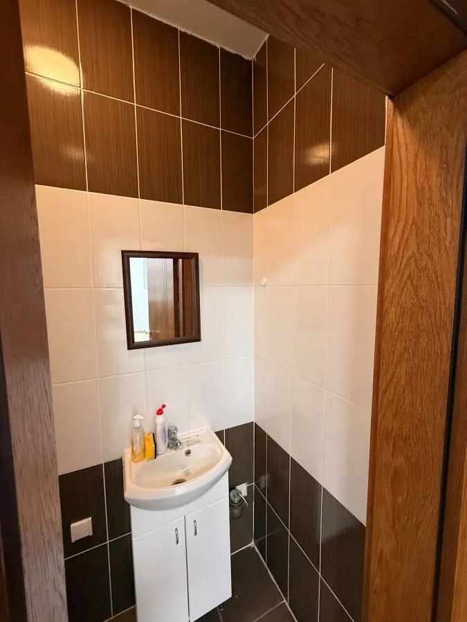 Small bathroom with a white basin, a mirror, and brown-and-white tiles.