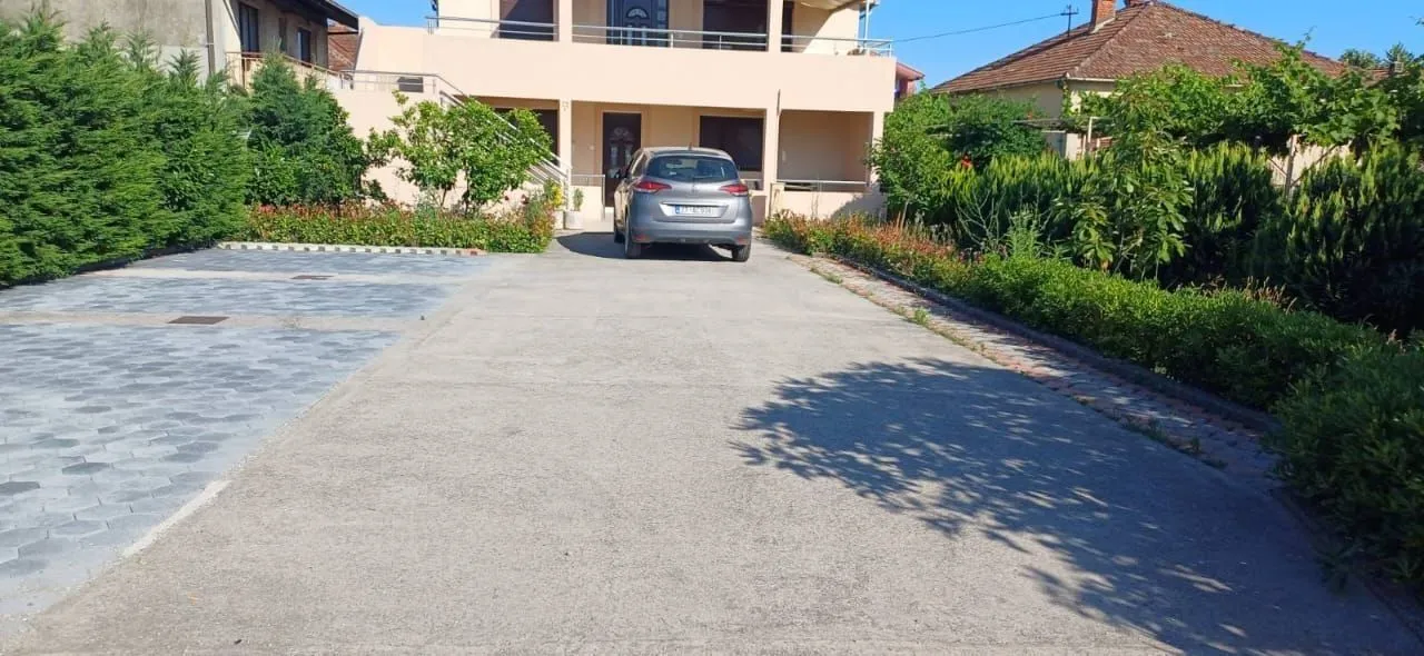 Paved driveway and spacious front yard of a family house with a parking space.