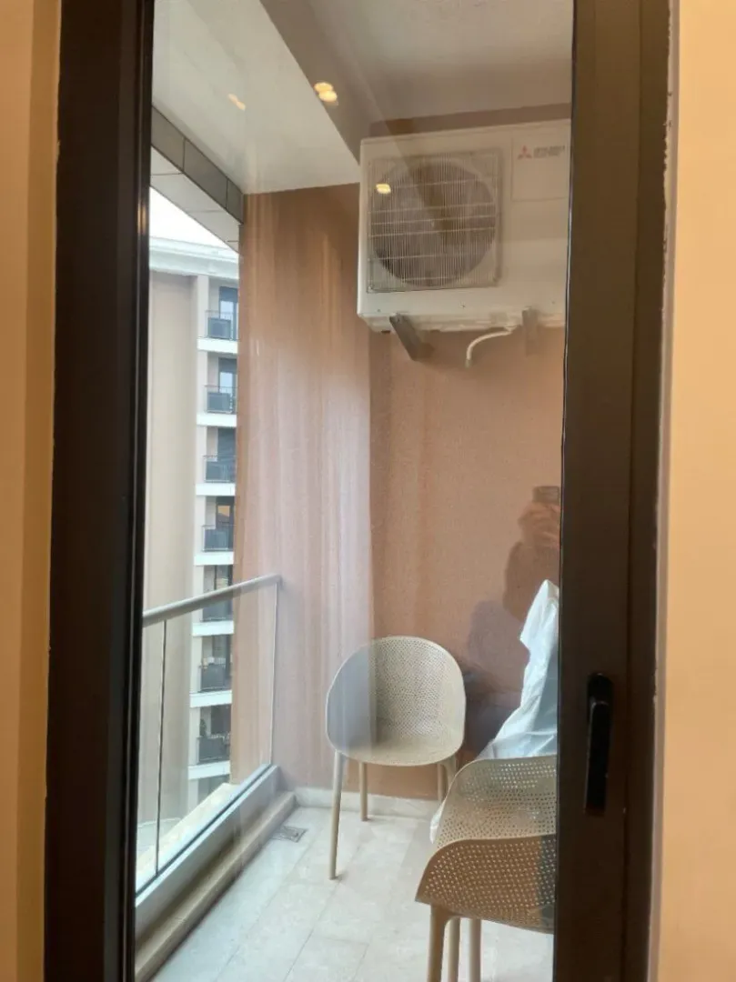 Small balcony with two chairs shot through a glass door.