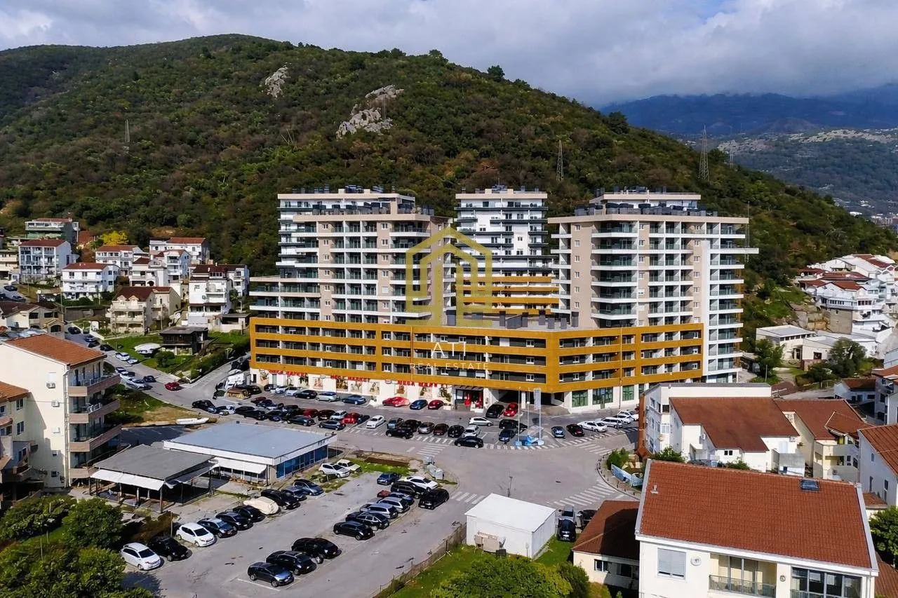 Pogled iz vazduha na stambeni kompleks sa parkingom i okruženjem.