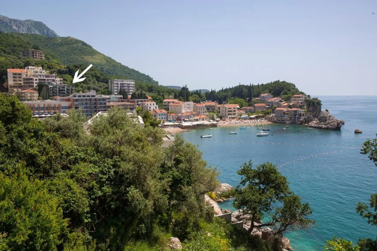 Pogled na zgradu i okolinu sa morem u pozadini.