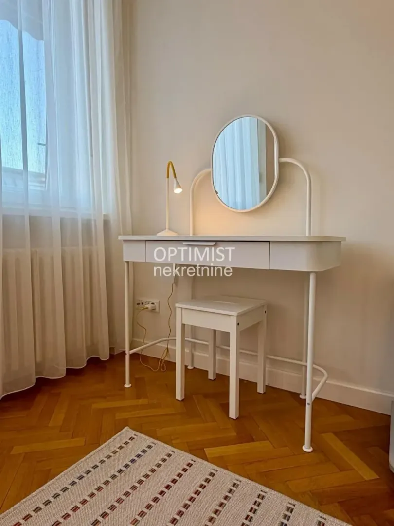 White dressing table with a mirror and a stool in the bedroom.