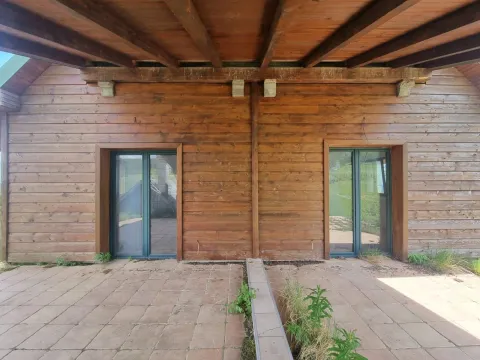 Drvena fasada kuće sa popločanom terasom i dvoja staklenih vrata. - image 14