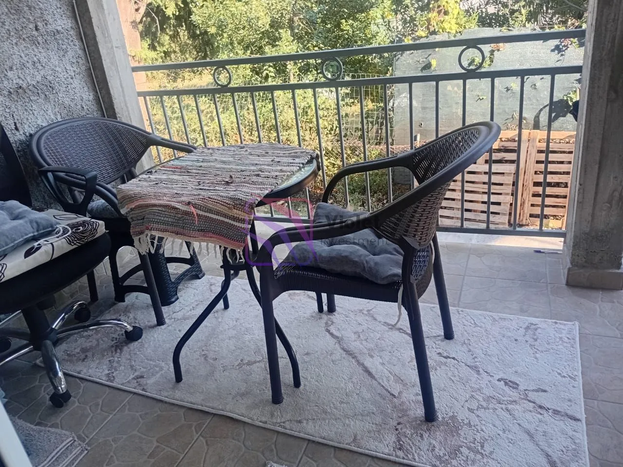 Furnished balcony with a table, chairs, and metal railing.