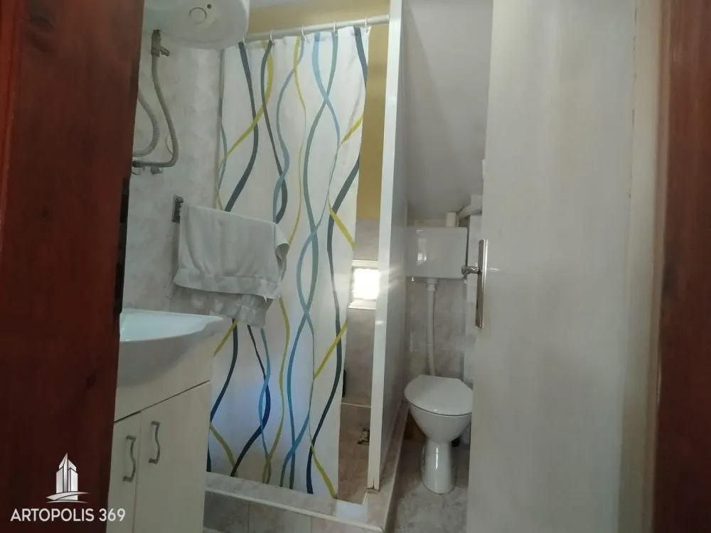 Pogled na kupatilo sa tuš kabinom, umivaonikom i wc šoljom.