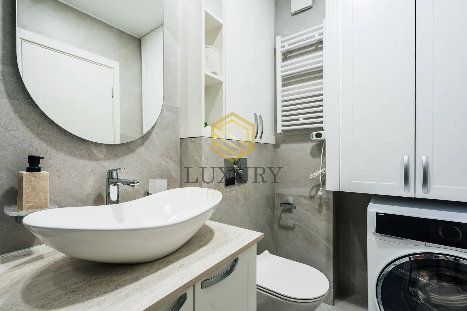 Modern bathroom with a washbasin, toilet, washing machine, and mirror.