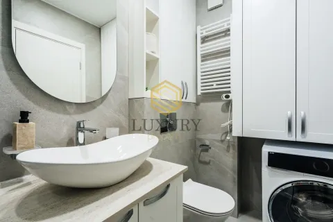 Modern bathroom with a washbasin, toilet, washing machine, and mirror. - image 9