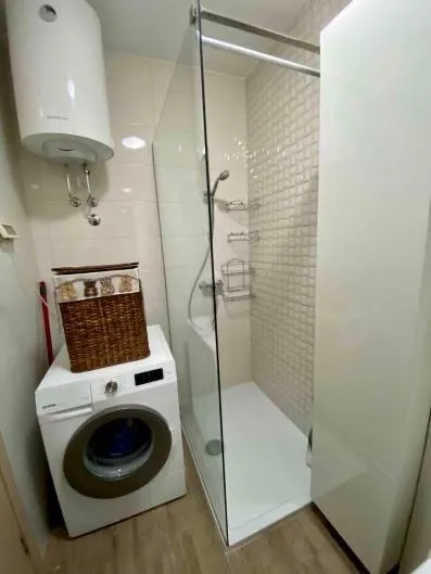 Small bathroom with a walk-in shower, washing machine, and water heater.