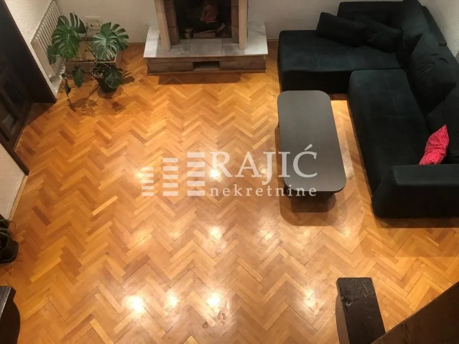 Living room with a sofa set, fireplace and parquet flooring.