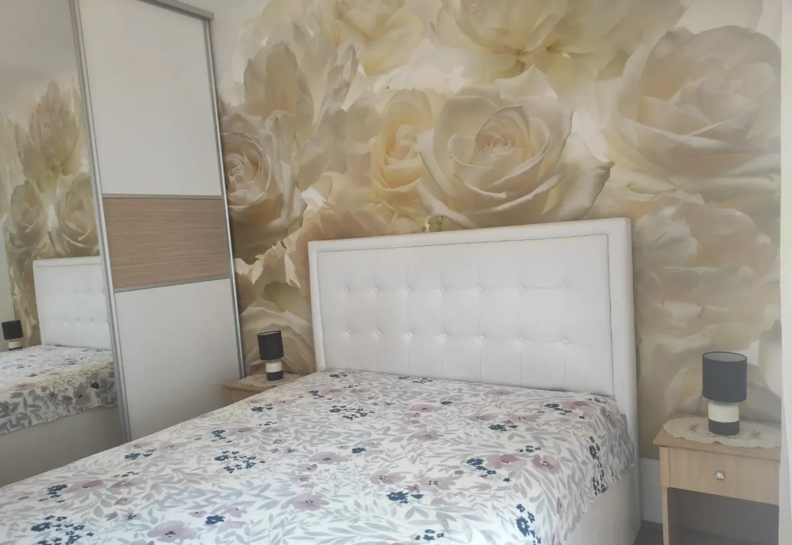 Bedroom with a double bed and rose-patterned wallpaper.