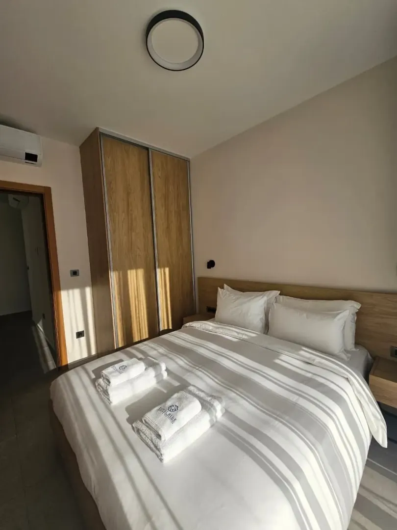 Moderna spavaća soba sa bračnim krevetom i drvenim garderoberom.