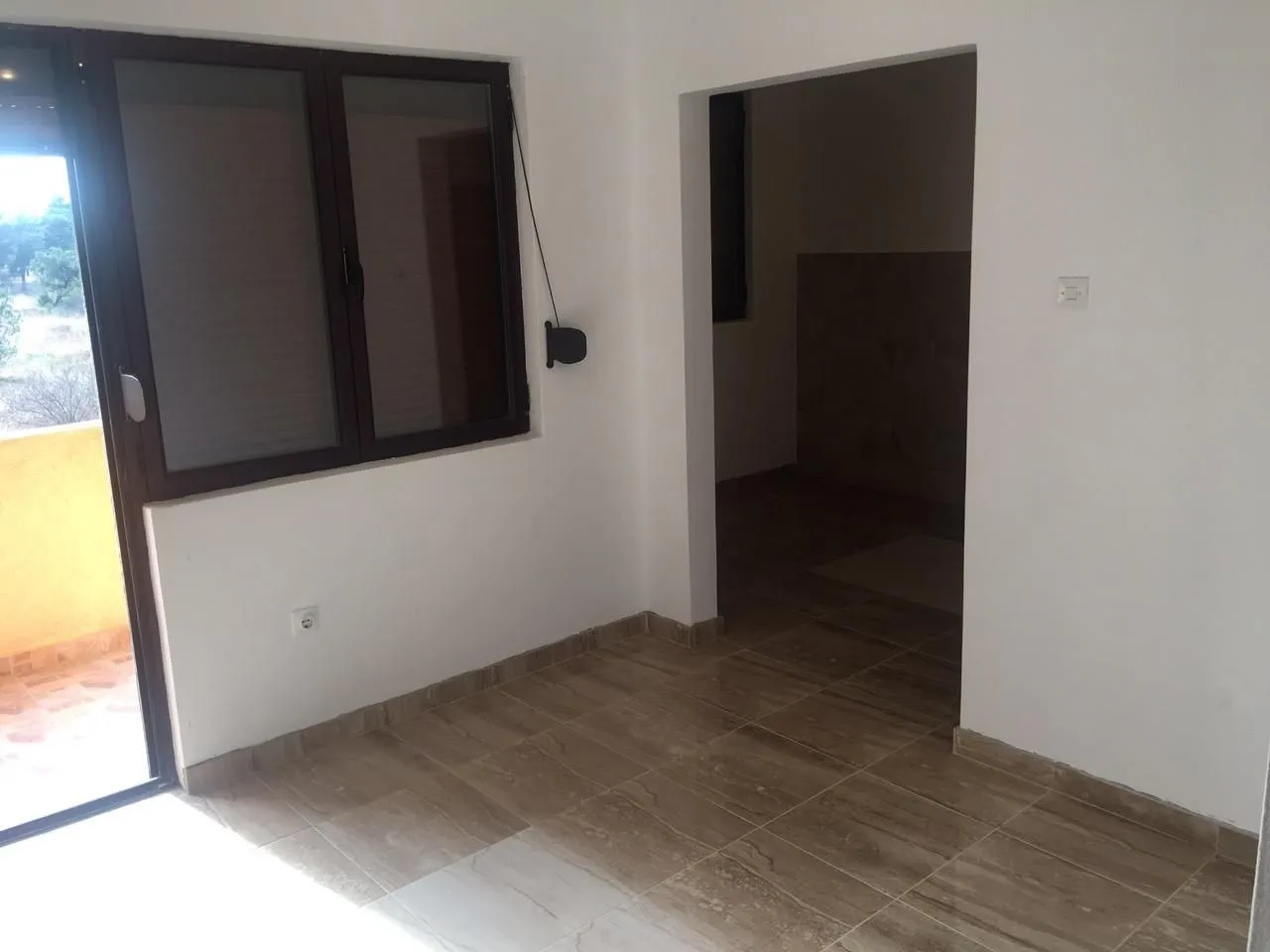 An empty room with tiled flooring and access to a balcony.