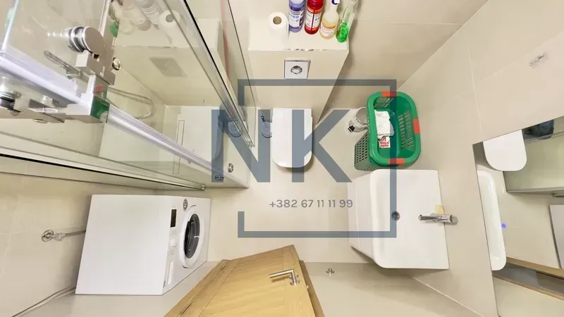 Top-down view of a modern bathroom with a glass shower enclosure and washing machine.