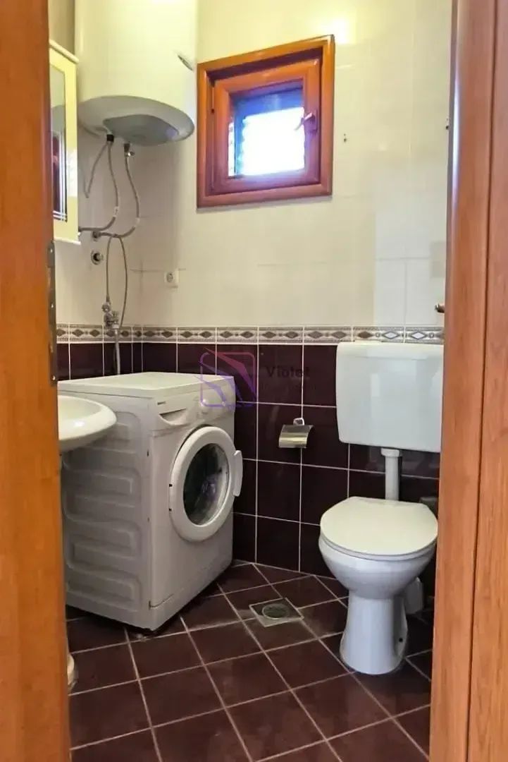 Manje kupatilo sa veš-mašinom, lavaboom i toaletom.