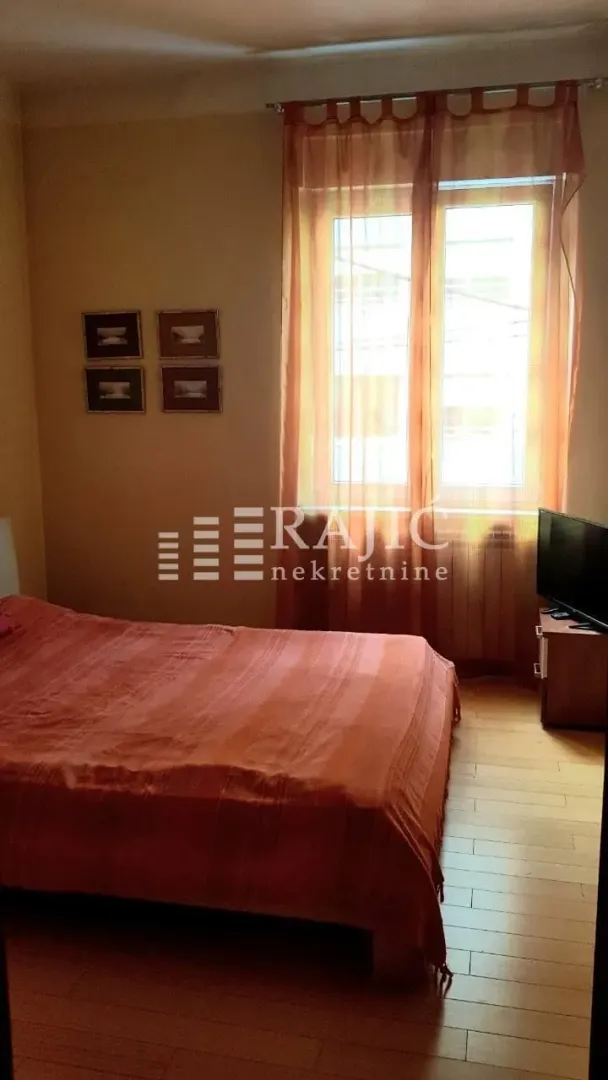 Bedroom with a double bed, window, and orange curtains.