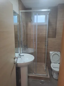 Small bathroom with a walk-in shower, washbasin, and toilet. - image 8