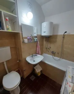Smaller bathroom with a bathtub, washbasin, and toilet. - image 8
