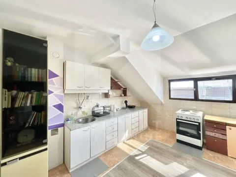 Attic kitchen with white cabinetry, stove, and bookshelves. - image 4
