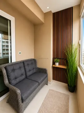 Zastakljeni balkon opremljen sivom pletenom sofom i drvenim dekorativnim panelima na zidu. - image 5