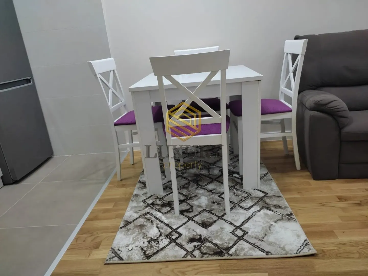 Trpezarijski sto sa bijelim stolicama i ljubičastim jastucima u dnevnom boravku.