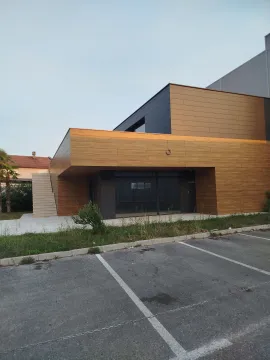 Exterior of a modern commercial building with a wooden facade and a parking lot in the foreground. - image 3