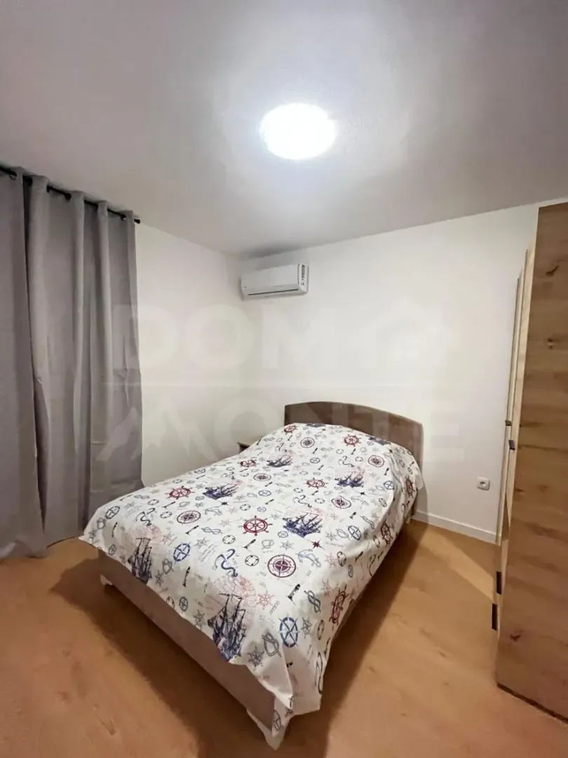 Manja spavaća soba sa bračnim krevetom, plakarom i klima uređajem.