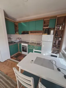 Kuhinja sa zelenim elementima i trpezarijskim stolom. - image 4
