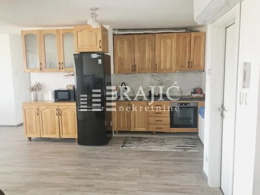 Wooden kitchen cabinets with a black refrigerator and built-in oven.
