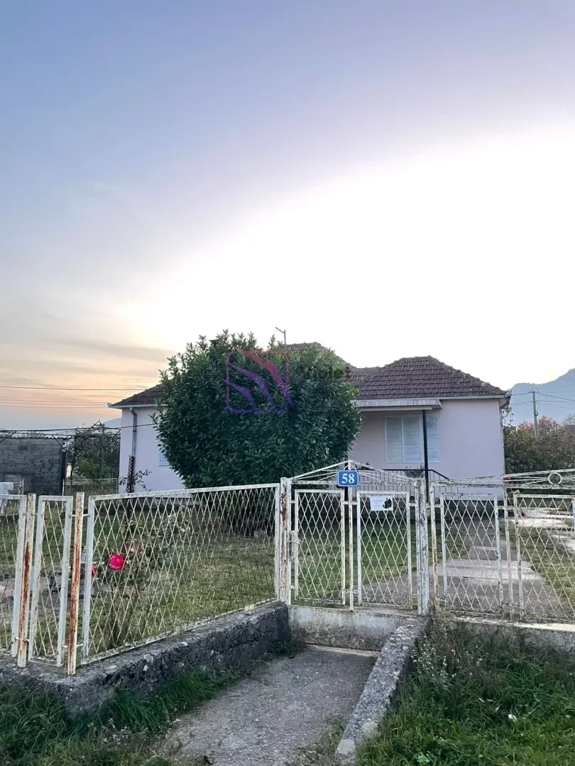 Pogled na dvorište i prednji dio porodične kuće sa ogradom.