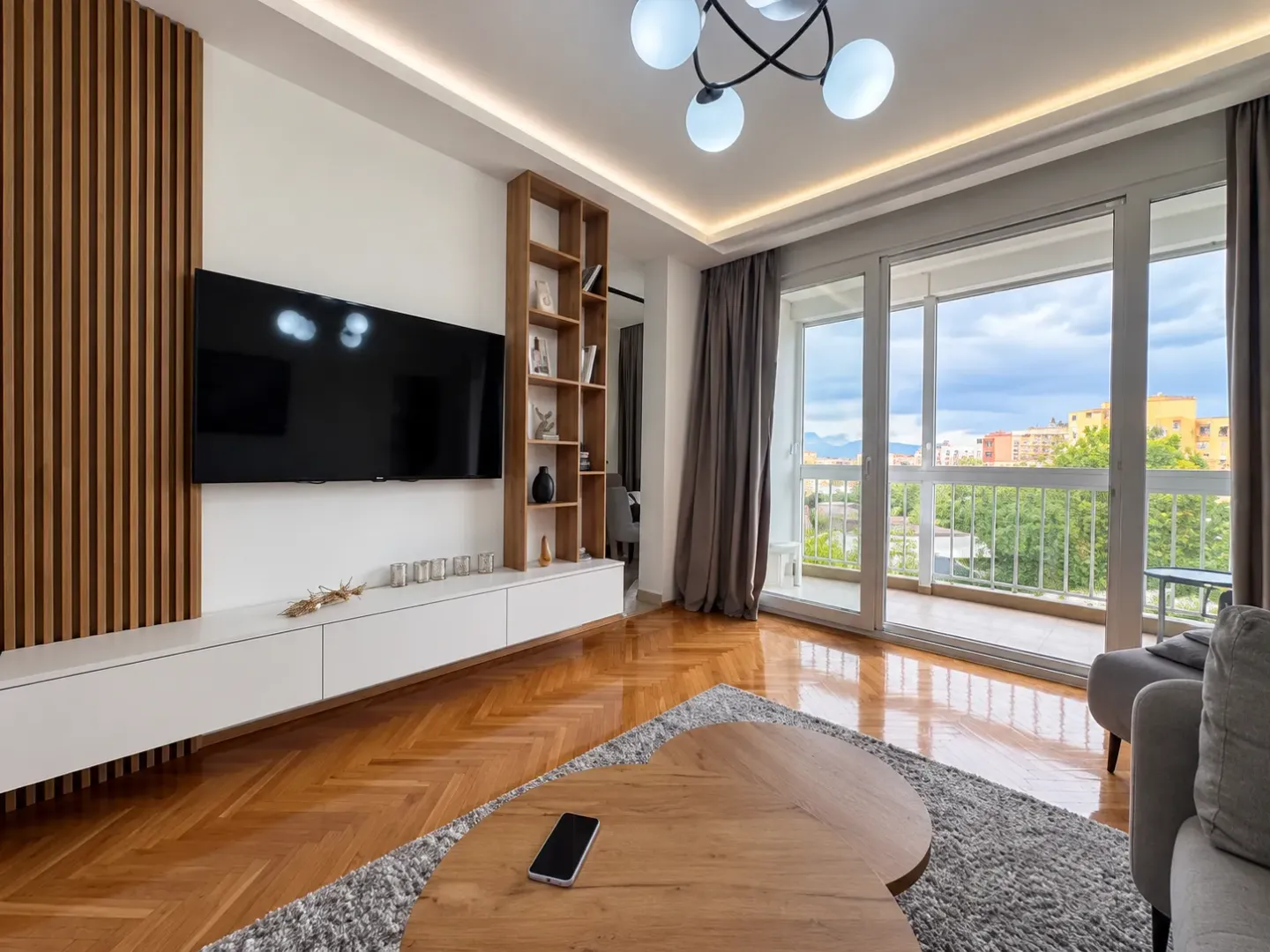 Living room with a television, wooden wall panels, and access to the terrace.