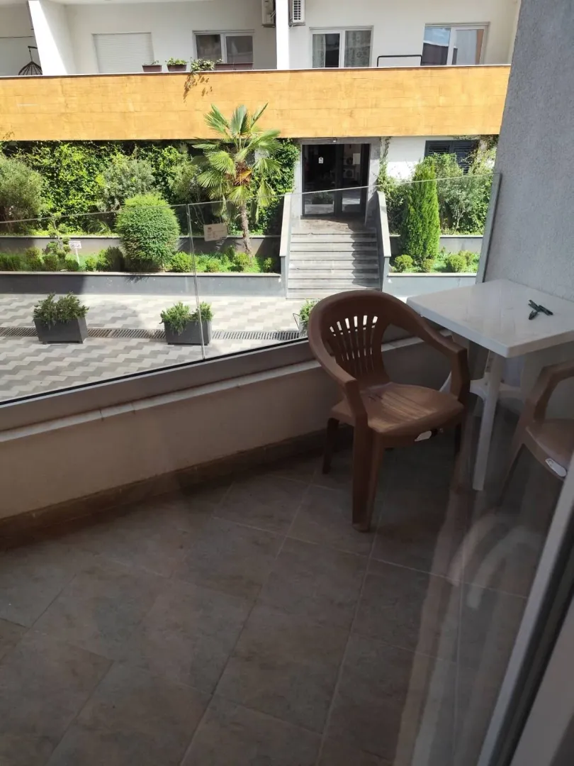 Small tiled balcony with a table and chairs overlooking the building's courtyard.