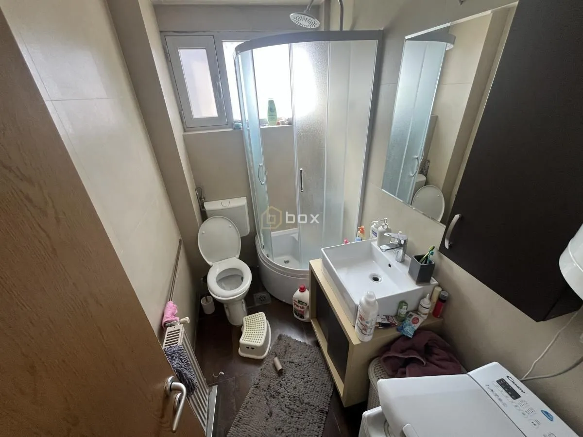 Manje kupatilo sa tuš kabinom, WC šoljom, umivaonikom i veš mašinom.