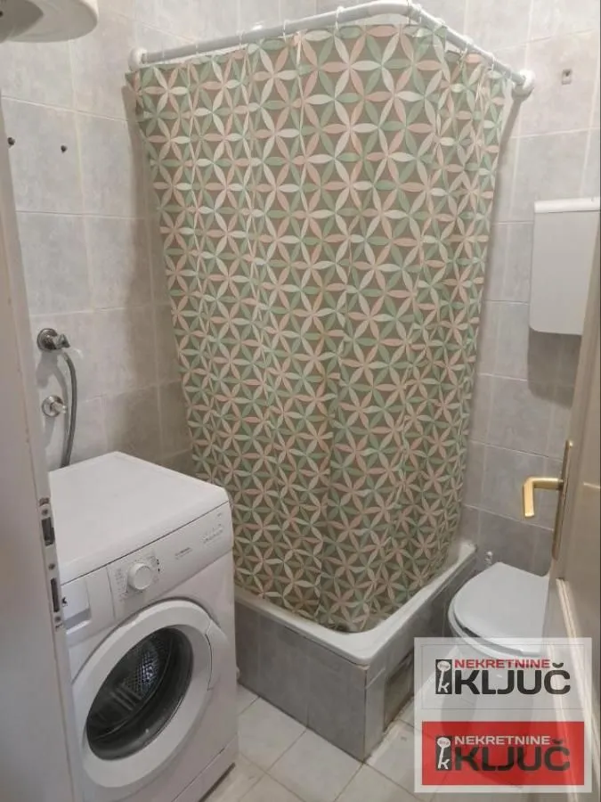 Manje kupatilo sa tuš kabinom, wc šoljom i veš mašinom.