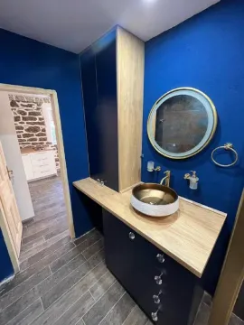 Moderne kupatilo sa umivaonikom, ormarićem i okruglim ogledalom na plavom zidu. - image 6