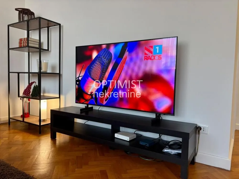 Living room with a television on a TV stand and a metal shelving unit.