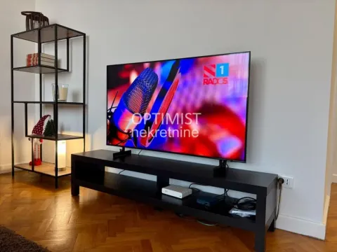Living room with a television on a TV stand and a metal shelving unit. - image 4