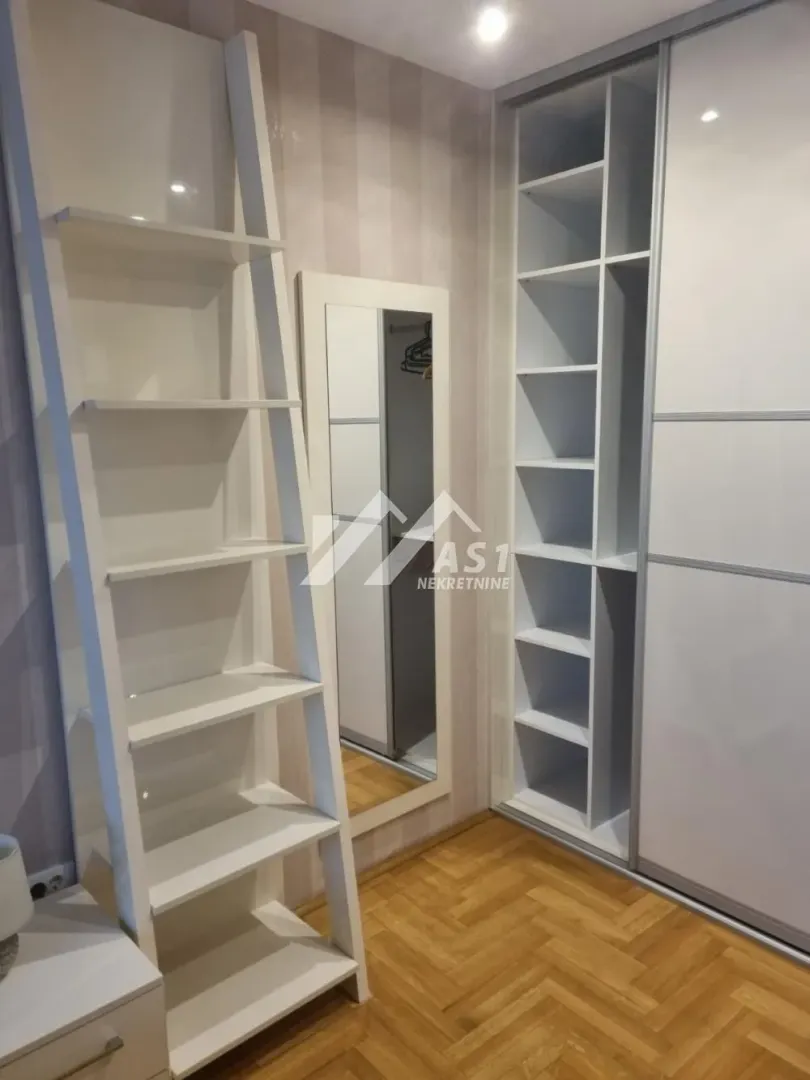 Spavaća soba sa ugradnim ormanom, policama i ogledalom.