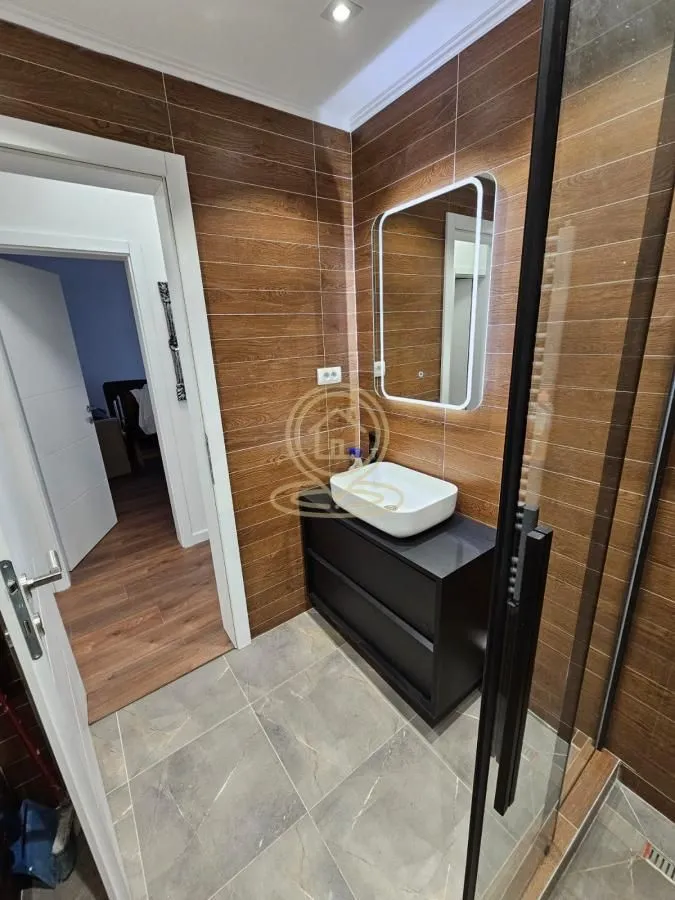 Bathroom with a washbasin, illuminated mirror, and shower cabin.