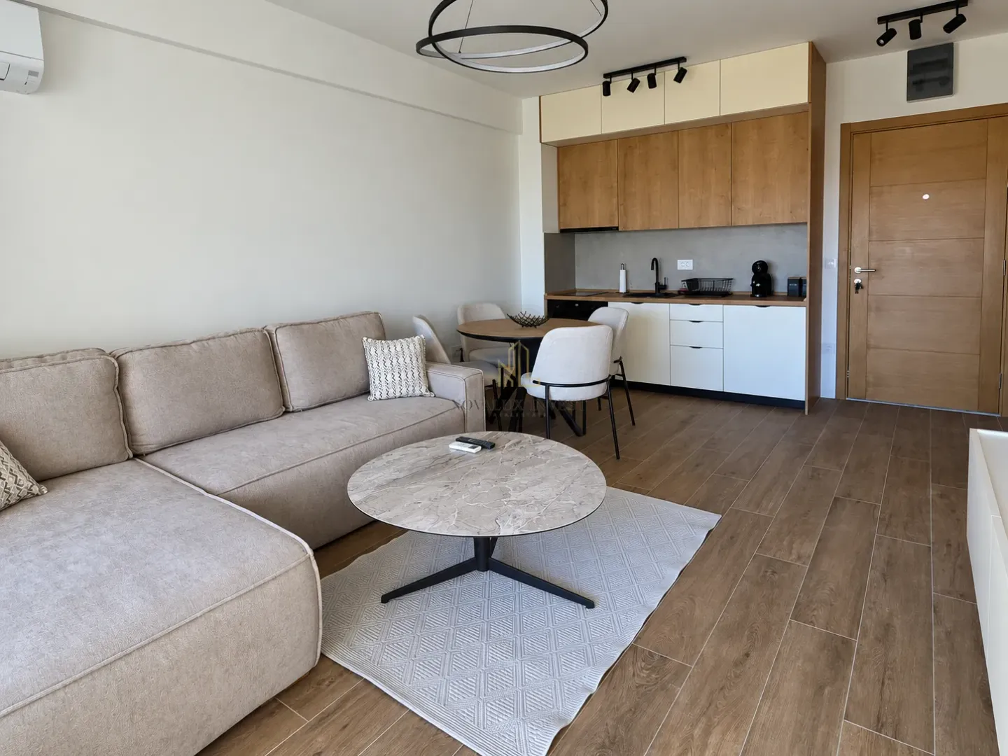 Living room with a sofa, coffee table, and a built-in kitchen in the background.