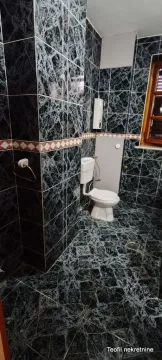 Bathroom tiled with dark marble tiles featuring a toilet. - image 17